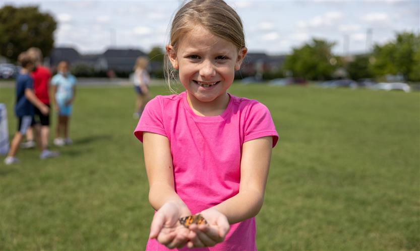 Students smile while releasing butterflies outside
